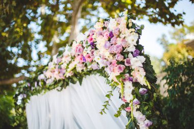 Düğün töreni açık havada. Taze çiçeklerle bembeyaz düğün kemeri.