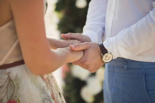 Braut und Bräutigam halten Händchen vor dem Hintergrund des Meeres. — Stockfoto