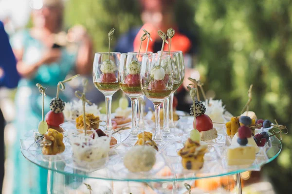 Réception au mariage. Snacks et verres à vin sur une table en verre . — Photo