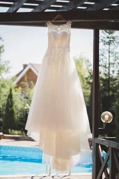 Elegantní svatební šaty v dřevěném altánku na pozadí bazénu během ranního shromáždění nevěsty. — Stock fotografie