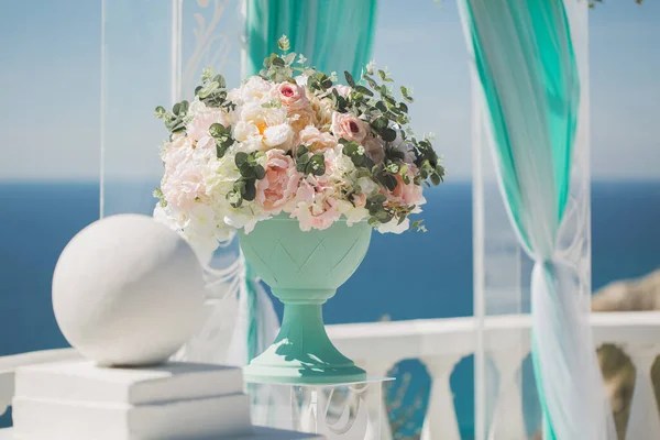 Bröllop arch för ceremonin och en vas med bröllop blommor, mot bakgrund av havet. — Stockfoto
