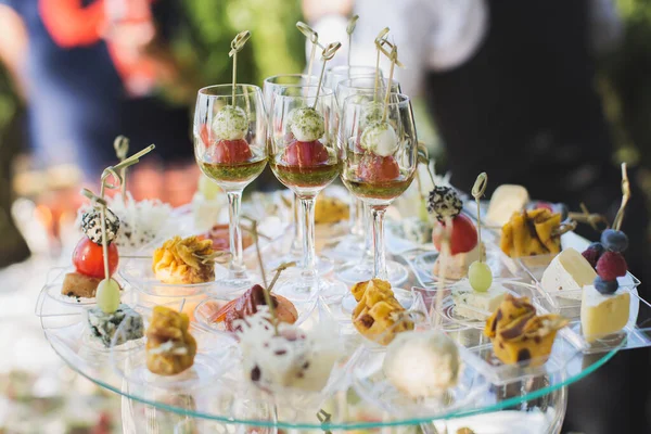 Recepce na svatbě. Svačinky a sklenice na víno na skleněném stole. — Stock fotografie
