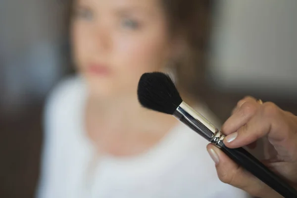 Close-up makeup brush on the background of the blurred face of the bride. — Stock Photo, Image