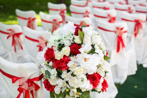 Cerimonia di matrimonio all'aperto. Sedie bianche con nastro rosso . — Foto Stock