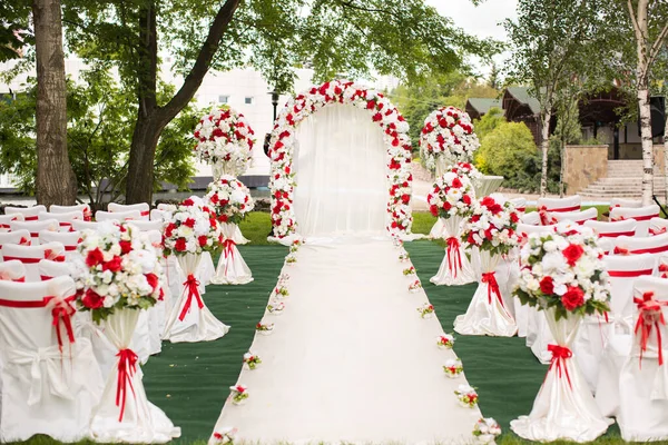 Cerimonia di matrimonio all'aperto. Arco da sposa decorato con fiori rossi . — Foto Stock