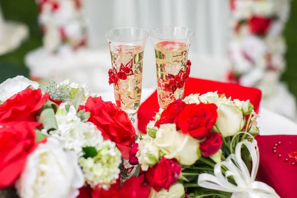 I bicchieri di champagne. Cerimonia di matrimonio all'aperto. Bouquet con fiori rossi . — Foto Stock