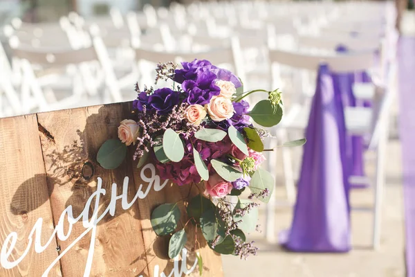 Wedding ceremony, purple flowers, white chairs on the street.
