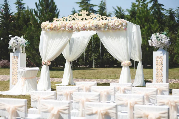 White wedding tent for the ceremony outdoors. Arch. Chairs.