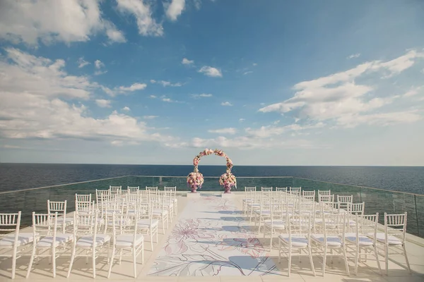 Arco de casamento com flores frescas em um fundo do mar. Vasos com flores frescas . — Fotografia de Stock