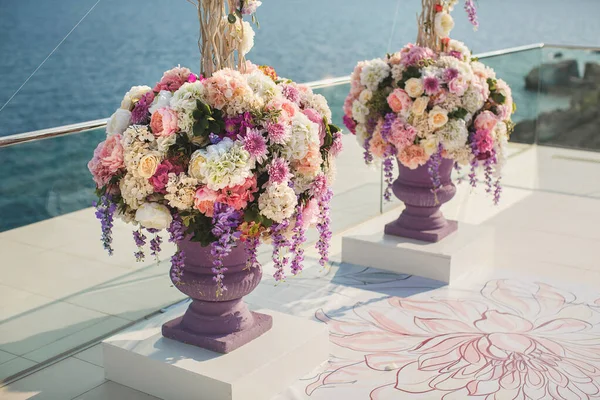 Färska blommor i en vas nära bröllopsvalvet mot havet. — Stockfoto