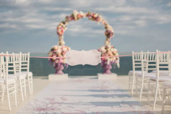 En skylt mot bakgrund av bröllopsbågen och havet. — Stockfoto