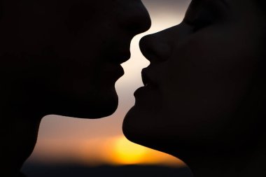 Gün batımında siluet sevgilileri. Gün batımında gün batımında genç bir çiftin siluetleri..