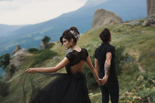 Mulher e homem de roupas pretas ao ar livre. Vestido de noiva preto . — Fotografia de Stock