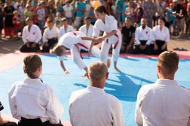 İki sporcu beyaz kimonoyla karate yapıyor..