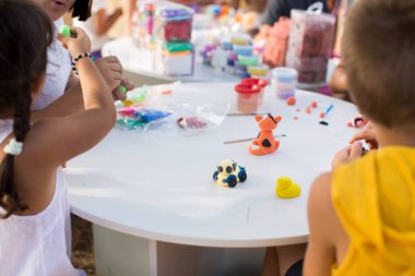 Çocukların elleri beyaz bir masanın üzerinde plastik kalıptan yapılır..