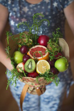 Orijinal olağandışı yenilebilir sebze ve meyve buketi kızın ellerinde..
