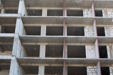 Çok katlı yeni bir bina inşa ediliyor. Gri tuğla ev.