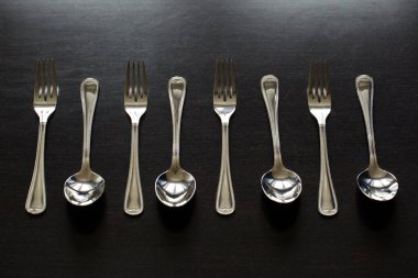 Siyah arka planda çatal bıçak takımı. Çatal, kaşık, bıçak.