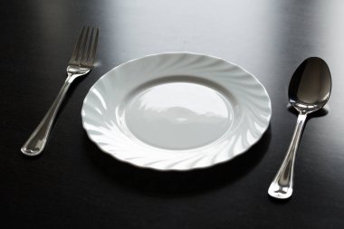 Siyah arka planda çatal bıçak takımı. Çatal, kaşık, bıçak, tabak.