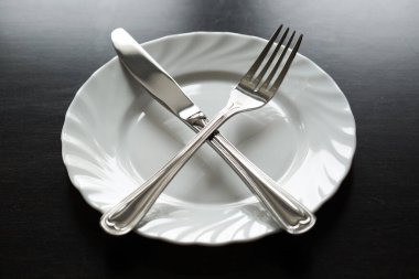 Siyah arka planda çatal bıçak takımı. Çatal, kaşık, bıçak, tabak.