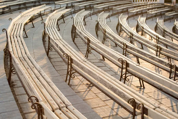 Fila di panchine di legno a teatro estivo in un parco di città . — Foto Stock