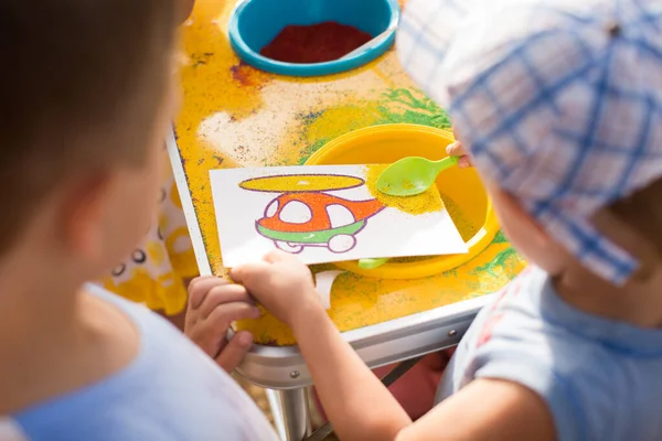 Ребенок рисует цветным песком. Персонажи мультфильмов . — стоковое фото