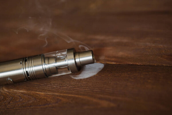 Electronic cigarette on a wooden table. Smoke.