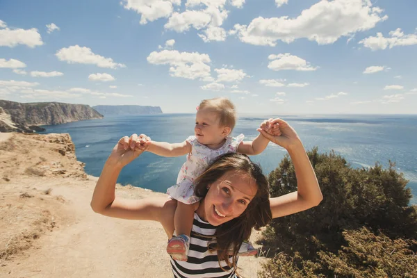 Mooie moeder en dochter buiten tegen de achtergrond van bergen en de zee. — Stockfoto