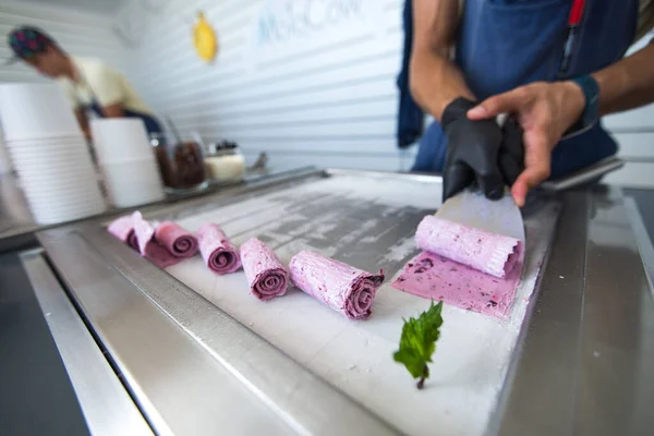 Stir-fried ice cream rolls at freeze pan. Rolled ice cream, hand made ice cream dessert. Fried ice cream machine with steel chilled pan.