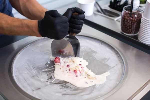 Stir-fried ice cream rolls at freeze pan. Rolled ice cream, hand made ice cream dessert. Fried ice cream machine with steel chilled pan.