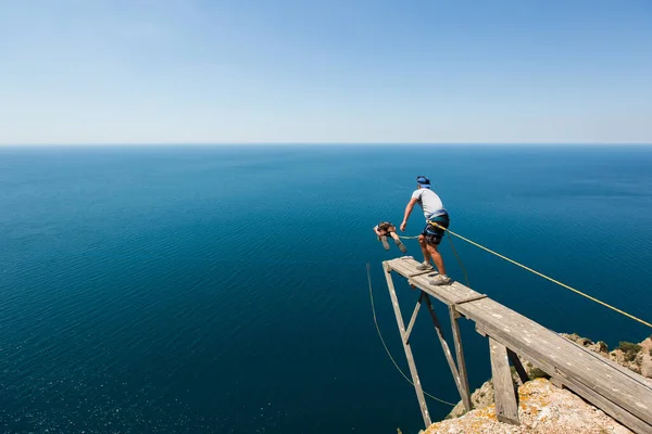 Rope jumping off a cliff with a rope in the water. The ocean. Sea. Mountain.