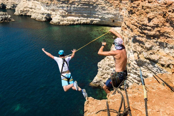 Rope jumping off a cliff with a rope in the water. The ocean. Sea. Mountain