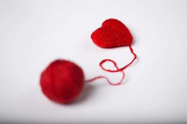 Primo piano di una palla di lana e forma di cuore su sfondo bianco. Filato di lana a forma di cuore. Amore all'uncinetto . — Foto Stock
