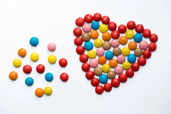 Caramelle di cioccolato a bottone colorate a forma di amore su sfondo bianco — Foto Stock