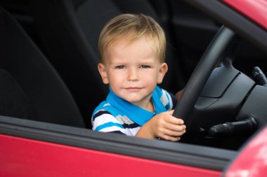 Babasının arabasını kullanan tatlı bir çocuk. Arabada çocuk var.