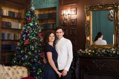 Noel atmosferinde Noel ağacı ve şömine yakınında el ele tutuşan erkek ve kadın..