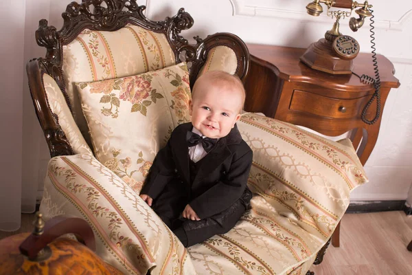 Child in a tuxedo sitting in an office talking on the phone. — Stock Photo, Image