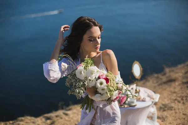 İç çamaşırlı gelin. Gelin buketini tutuyor. Gelinin görevleri, gelinler sabahı. — Stok fotoğraf