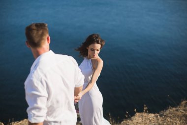 Bir adam ve bir kız okyanus geçmişiyle dağın yamacında yürüyorlar..