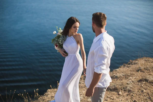 Ein Mann und ein Mädchen gehen am Abgrund des Berges mit dem Hintergrund des Ozeans. — Stockfoto