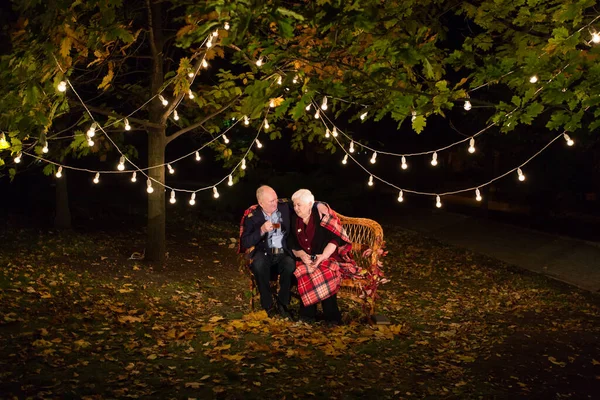 Děda a babička pijou čaj v parku. — Stock fotografie