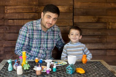 Baba ve oğul tahta bir duvara karşı boyayla oynuyorlar..