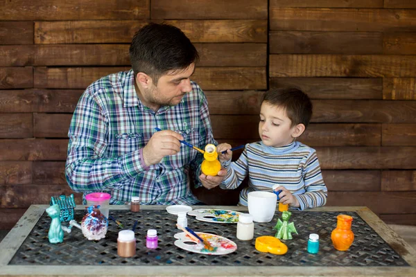 Father and son in the Studio of paint a vase.