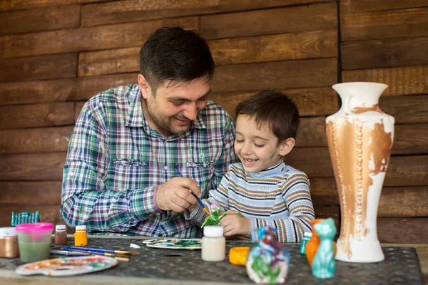 Отец и сын рисуют краски на деревянной стене . — стоковое фото