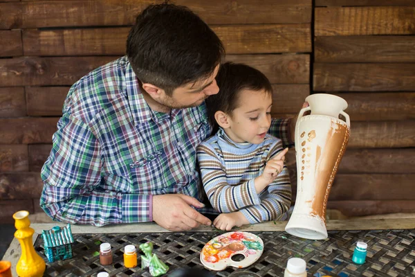 Отец и сын рисуют вазу на деревянной стене. . — стоковое фото