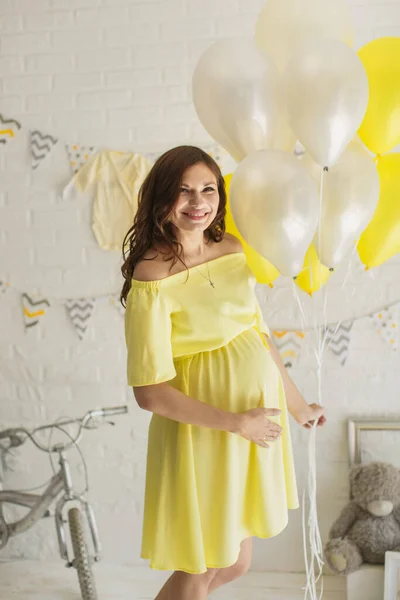 Mooie zwangere vrouw in een gele jurk in de Studio. — Stockfoto