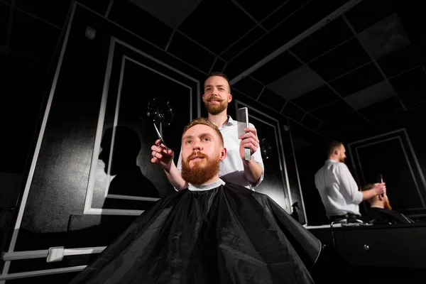 Master taglia capelli e barba nel negozio di barbiere. Il parrucchiere fa l'acconciatura usando forbici e un pettine in metallo . — Foto Stock