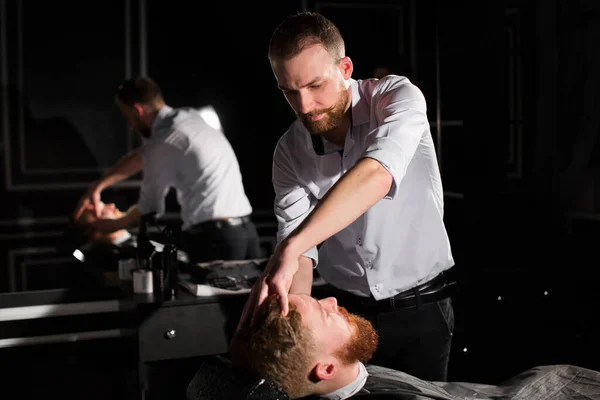 Il parrucchiere sta radendo la barba maschile con il coltello. bello barbuto uomo è ottenere rasato da parrucchiere a il barbiere . — Foto Stock