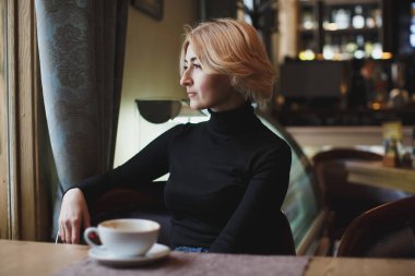 Güzel bir kadın beyaz bardaktan kahve içiyor..