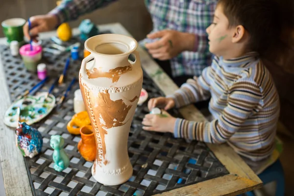 Vater und Sohn malen Vase gegen Holzwand. — Stockfoto